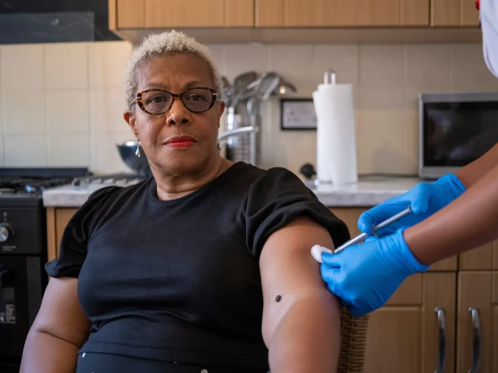 Nurse giving injection to patient at home