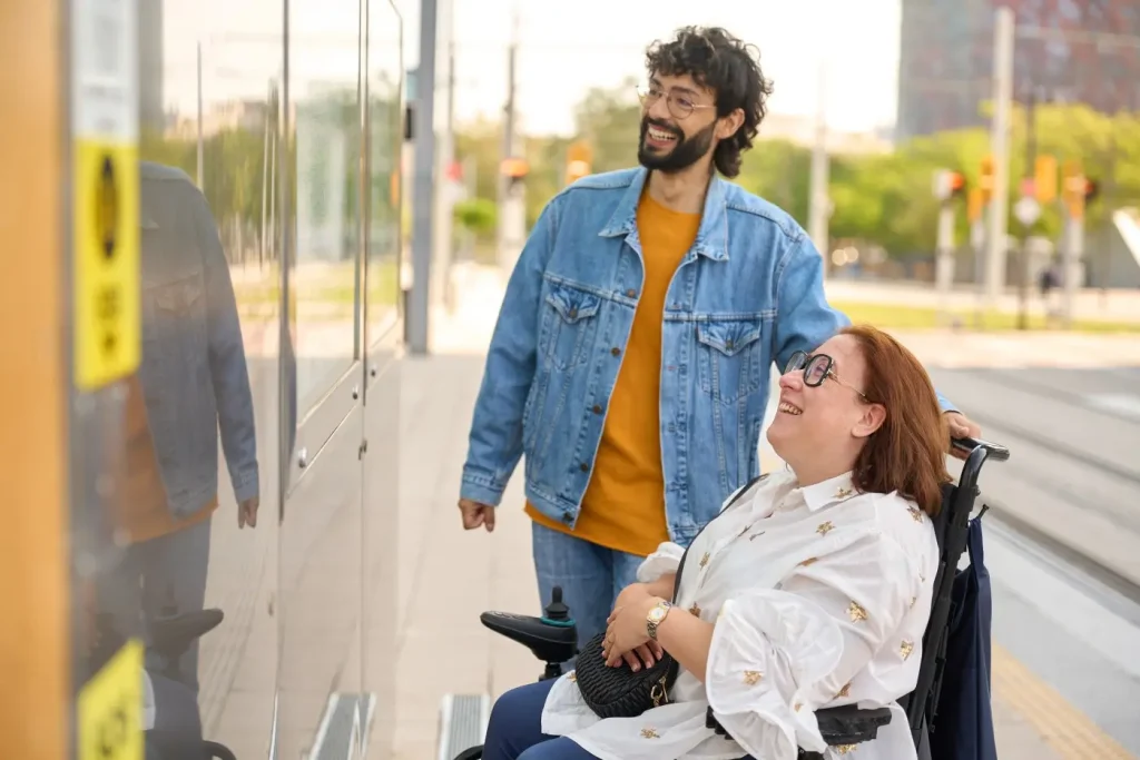 Disabled woman in wheelchair with friend at tram stop